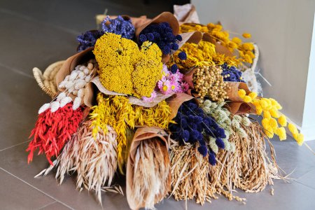 Téléchargez les photos : Bouquets arrangés de fleurs colorées en fleurs assorties empilées sur le sol carrelé dans la pièce à lumière - en image libre de droit
