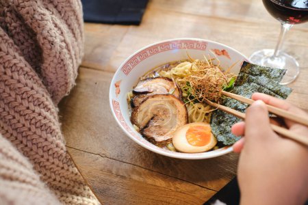 Photo for From above of crop anonymous person eating tasty ramen with chopsticks while having lunch on table - Royalty Free Image