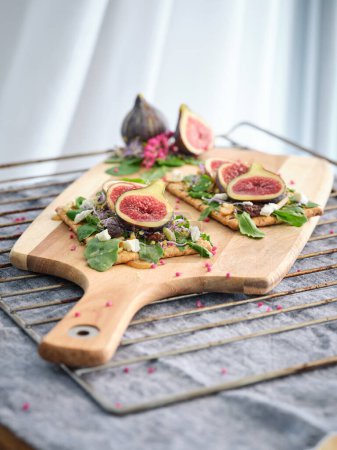 Photo for High angle of delicious toasts with fruits on wooden cutting board placed on table - Royalty Free Image