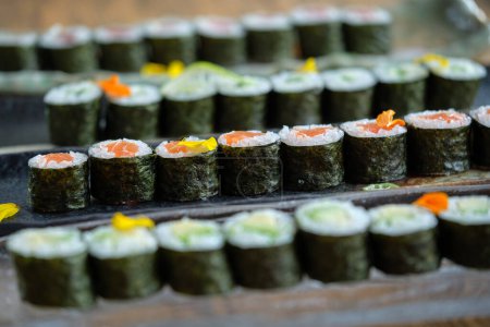Téléchargez les photos : Plateaux en marbre avec rouleaux de sushi au saumon placés sur une table en bois sur fond flou - en image libre de droit
