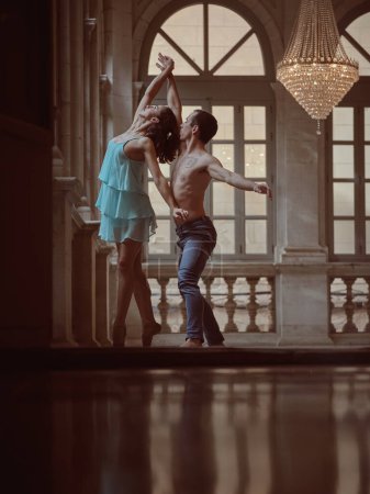 Foto de Vista lateral de la dama en vestido y puntiagudo y artista de ballet sin camisa durante la danza sincrónica en el salón de baile del palacio - Imagen libre de derechos