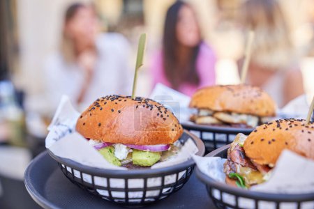 Téléchargez les photos : Délicieux hamburgers avec viande et légumes sur des brochettes en bois servis dans des paniers sur la table dans un café extérieur - en image libre de droit