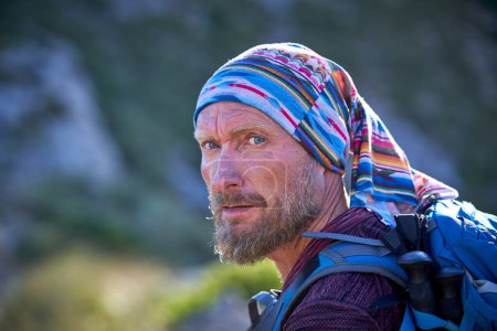 Photo for Side view of middle aged bearded male hiker with backpack looking away during trekking in nature on sunny day - Royalty Free Image