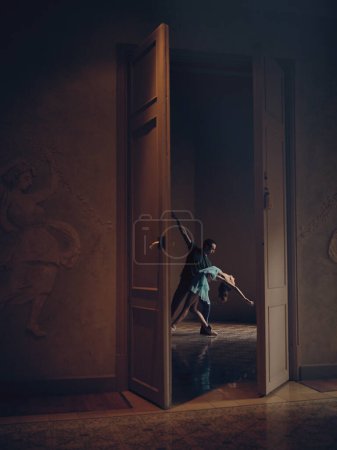 Foto de Bailarina irreconocible y dama en punta pasando tiempo en habitación oscura con puerta abierta en la catedral - Imagen libre de derechos