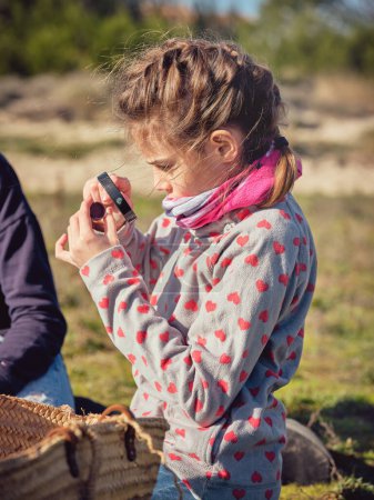 Photo for Side view of cute concentrated preteen girl observing piece of waste plastic through magnifying glass in nature - Royalty Free Image