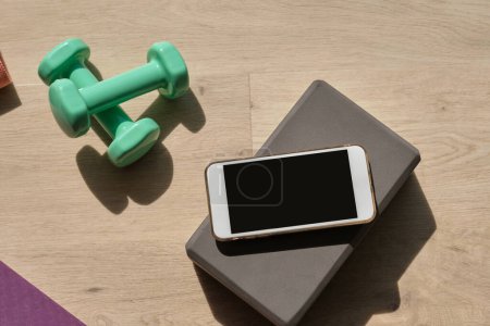 Foto de Desde arriba de aparatos de fitness y teléfonos inteligentes modernos colocados en el suelo en la habitación en un día soleado - Imagen libre de derechos