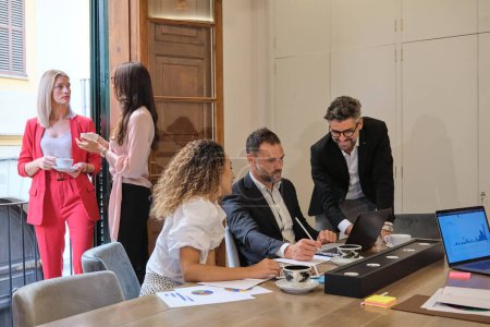 Téléchargez les photos : Groupe de collaborateurs positifs portant des tenues formelles élégantes discutant dans un bureau léger - en image libre de droit