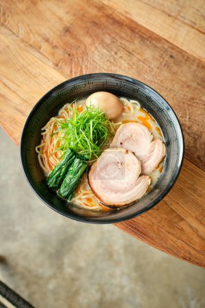 High angle of bowl of palatable ramen noodle soup with chashu nori broth and egg served on wooden table in Japanese restaurant