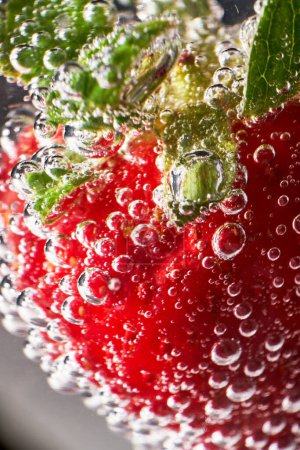 Téléchargez les photos : Gros plan fraise rouge mûre avec bulles de dioxyde de carbone flottant dans un verre de boisson fraîche - en image libre de droit