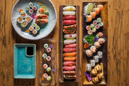 Photo for Top view of various sushi with assorted fish near rolls with different topping served on wooden table in light cafe - Royalty Free Image