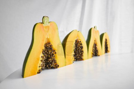 Téléchargez les photos : Vue latérale du bouquet de délicieux fruits de papaye frais mûrs coupés en morceaux et disposés sur une table grise avec des graines et placés ensemble - en image libre de droit