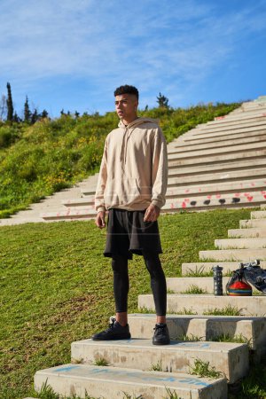 Photo for Full body of confident Hispanic male in sportswear standing on stone steps during outdoor training in city on summer day - Royalty Free Image