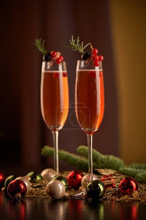 Téléchargez les photos : Verres au champagne décorés de baies servies sur table avec des branches de conifères vertes et des boules de Noël colorées lors d'un événement festif - en image libre de droit