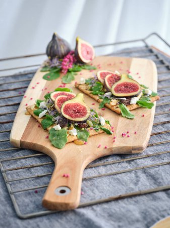 Photo for High angle of delicious vegetarian toasts with fresh fruits and herbs placed on wooden cutting board in kitchen - Royalty Free Image