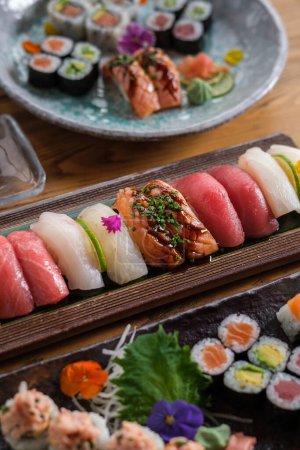 Téléchargez les photos : D'en haut abondance de délicieux sushis et rouleaux avec différents poissons colorés servis sur assiette et plateaux dans un café léger - en image libre de droit
