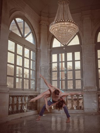 Foto de Cuerpo completo de hombre anónimo sin camisa con bailarina flexible en la espalda bailando en el suelo cerca de la ventana en la impresionante sala - Imagen libre de derechos