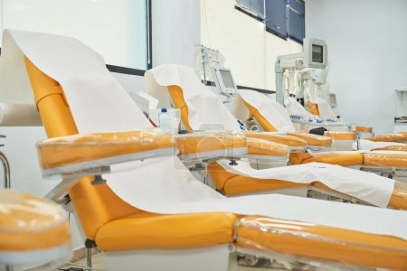 Téléchargez les photos : Chaises modernes orange avec accoudoirs et couvertures blanches pour les patients assis dans un centre de don professionnel - en image libre de droit