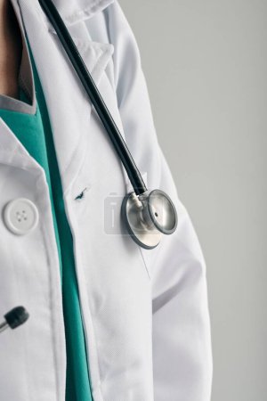 Téléchargez les photos : Crop médecin anonyme en uniforme médical blanc avec stéthoscope professionnel au travail sur fond clair - en image libre de droit