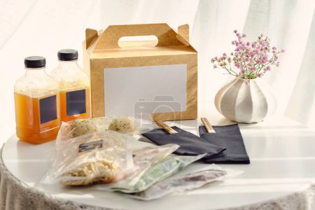 Photo for Composition of ramen soup ingredients in vacuum bags alongside carton box and bottles with stock on table in light room - Royalty Free Image