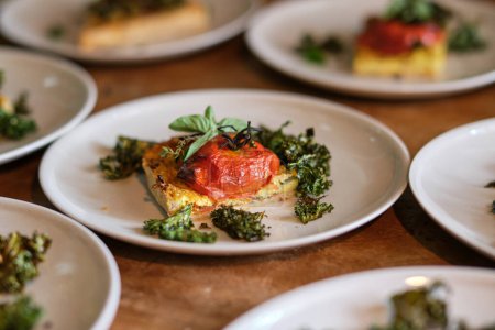 Téléchargez les photos : Tranches de pizza végétaliennes appétissantes avec des feuilles de tomate et de basilic frais sur les assiettes en céramique - en image libre de droit