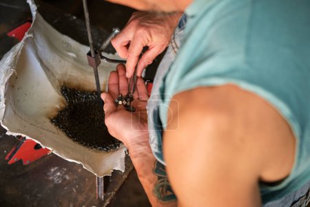 Photo for High angle of crop anonymous male worker putting small metal pieces into mold for welding at workbench in shabby garage - Royalty Free Image