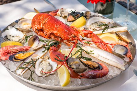 Spectaculaire homard aux moules, crevettes, palourdes et palourdes rasées présenté sur une assiette avec glace. Avec vue spectaculaire sur la mer à Majorque.