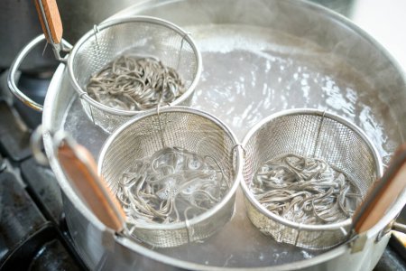 Photo for High angle of metal strainer baskets with soba noodles boiling in saucepan for cooking traditional Asian food - Royalty Free Image