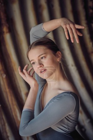 Téléchargez les photos : Jolie jeune danseuse de ballet avec bras levé regardant au loin tout en dansant gracieusement dans un vieux tunnel aux murs minables - en image libre de droit