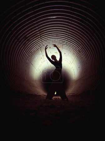 Foto de Cuerpo completo de talentosas bailarinas de ballet en zapatos puntiagudos bailando en un viejo túnel abandonado con paredes y piedras - Imagen libre de derechos
