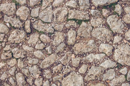Téléchargez les photos : Vue de dessus du fragment de chemin de pierre brute avec surface texturée en journée comme fond abstrait - en image libre de droit