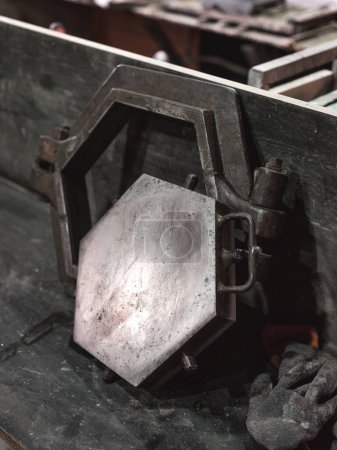 Téléchargez les photos : Moule en métal minable en forme d'hexagone avec prise de vice pour la fabrication de carreaux de céramique suspendus au mur dans un atelier artisanal - en image libre de droit