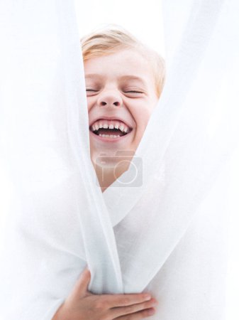 Photo for Adorable boy laughing with closed eyes and mouth opened covering body with white curtain - Royalty Free Image