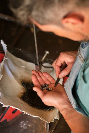 Foto de Alto ángulo de cultivo trabajador masculino anónimo poniendo pequeñas piezas de metal en el molde para soldar mientras trabaja en un taller profesional - Imagen libre de derechos