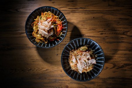 Photo for Top view of appetizing noodles and fried rice with tomato sauce placed on wooden table together in light of restaurant - Royalty Free Image