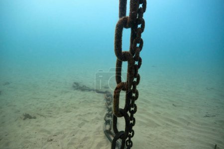 Téléchargez les photos : Gros plan des chaînes de fer d'ancrage à la surface de la mer et dans l'eau de mer bleu profond alors qu'elles tombaient à faible profondeur et arrêtaient le bateau - en image libre de droit