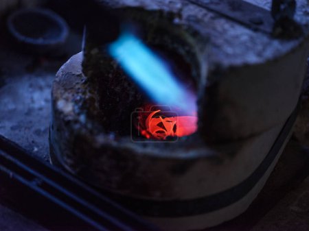 Foto de Desde arriba enfoque selectivo de la quema de gas de fundición de la antorcha de metal en el horno en orfebre taller - Imagen libre de derechos