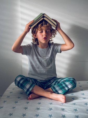 Photo for Full body of barefoot preteen boy putting books on head and fantasying with closed eyes - Royalty Free Image