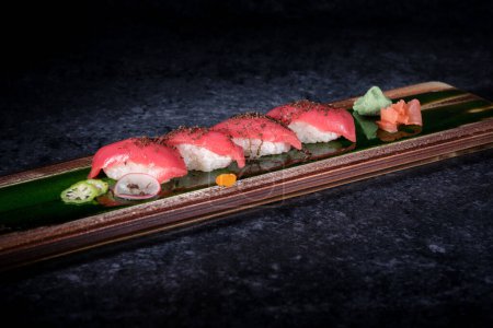 Foto de Delicioso sushi nigiri japonés con pescado fresco y arroz decorado con jengibre y wasabi conservados y rebanada delgada de rábano y lima - Imagen libre de derechos