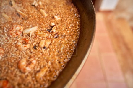 Photo for From above part of metal pan with boiling palatable Spanish meal against blurred backdrop - Royalty Free Image