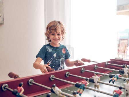 Photo for Adorable preteen boy in t shirt playing foosball in playroom of hotel - Royalty Free Image