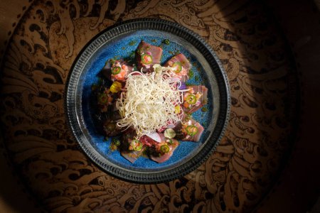Téléchargez les photos : Tranches de thon germon avec radis daikon râpé servi sur une assiette en céramique sur la table dans la pièce lumineuse - en image libre de droit