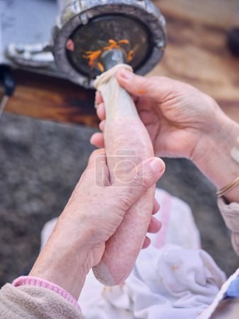 Téléchargez les photos : Vue latérale du boyau de saucisse de remplissage féminin senior méconnaissable avec de la viande hachée de la machine tout en préparant un chorizo savoureux dans la boucherie traditionnelle à Majorque - en image libre de droit