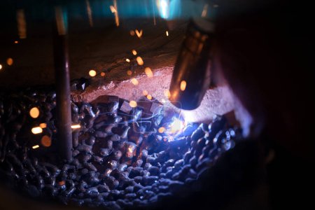 Foto de De arriba artesano anónimo utilizando la máquina para soldar metal alrededor de palo en el molde de yeso durante el trabajo en el taller tenue - Imagen libre de derechos