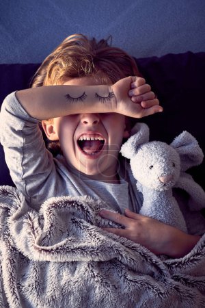 Téléchargez les photos : Heureux petit garçon couvrant les yeux avec la main. yeux peints sur la main enfant tenant, jouet lapin - en image libre de droit