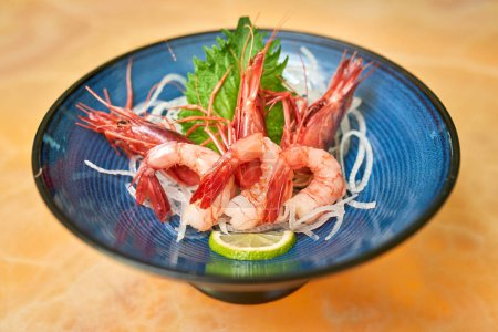 Photo for High angle of tasty prawns with lime slice and onions placed on table in Asian restaurant - Royalty Free Image