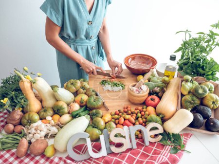 Photo for From above of crop anonymous housewife cutting fresh ripe vegetables on chopping board while preparing healthy vegetarian food of various ingredients - Royalty Free Image