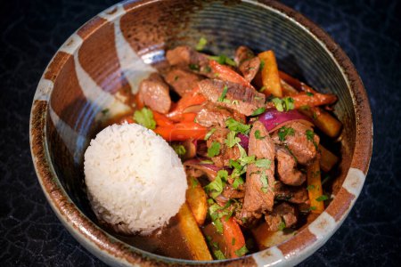 Photo for High angle of delicious food of stir fry beef with boiled vegetables and cooked rice served in ceramic bowl on black background - Royalty Free Image
