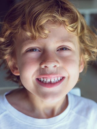 Photo for Portrait of adorable kid with wavy blond hair and brown eyes looking at camera with toothy smile - Royalty Free Image