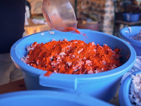 Photo for From above of unrecognizable person adding red paprika in beef mince in blue bowl while preparing sausage in butchery in Mallorca - Royalty Free Image