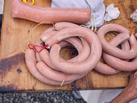 Photo for Side view of arranged prepared sausage in casing of pork guts and bound with culinary cord placed on wooden table in village of Matanza in Mallorca - Royalty Free Image
